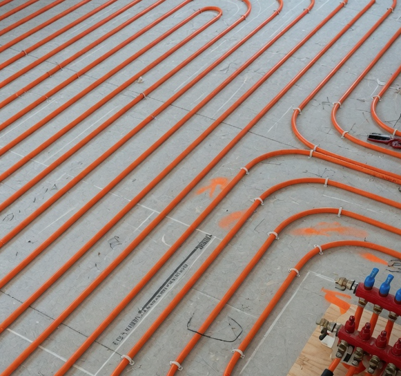 Thin underlayment being laid over a radiant heating system before laminate installation in Aurora, IL.