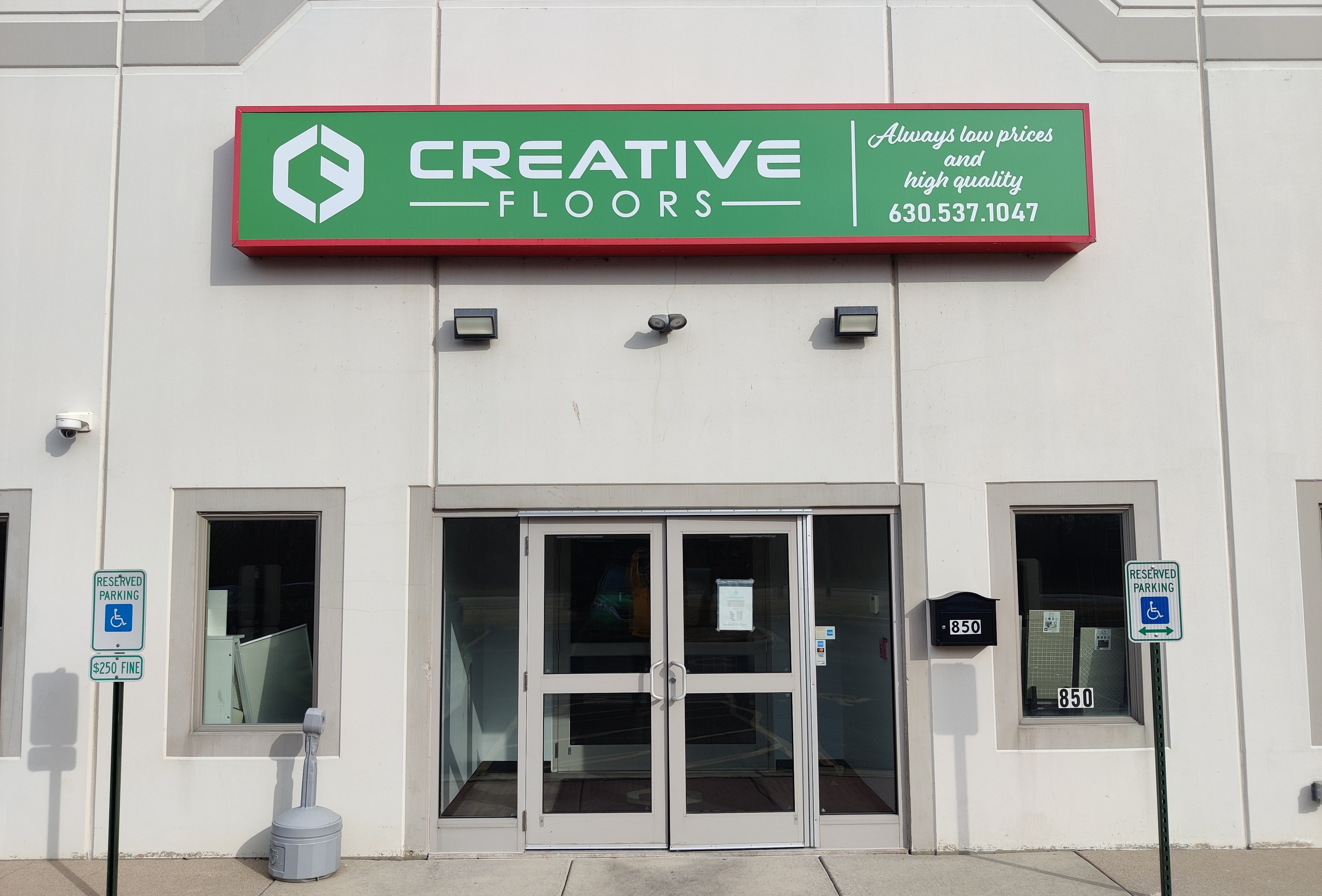 Sign for Creative Floors with text about low prices and quality, entrance with door and windows.